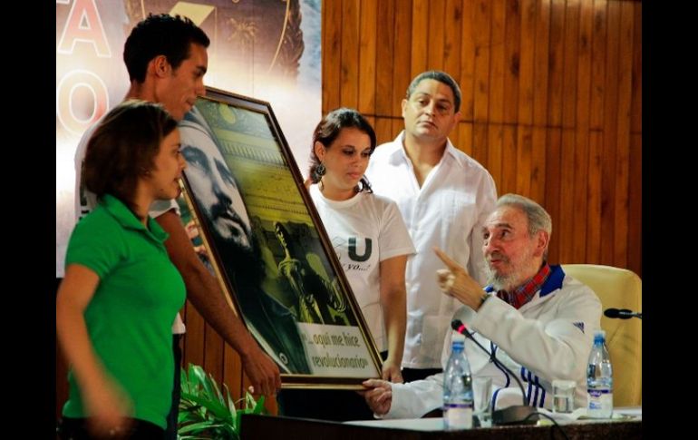 Fidel Castro (d), habla con los estudiantes mientras recibe un cuadro en el que es representado de joven. AP  /