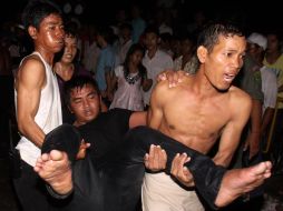 Voluntarios alejan a un herido tras la tragedia en el puente que conecta a la Isla Diamante con Phnom Penh, en Camboya. AP  /