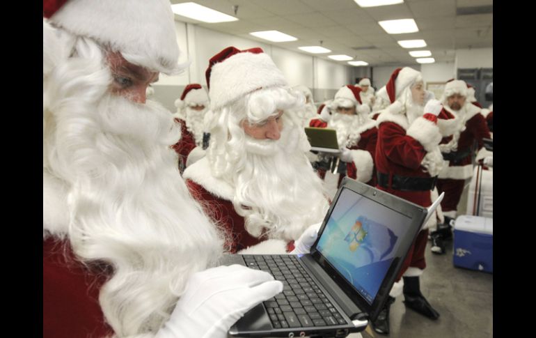 Empleados de una aerolinea se disfrazan de Santa Claus en unión con Microsoft para agazajar a sus clientes. AP  /