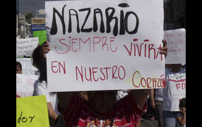 Un hombre sostiene un cartel que dice ‘‘Nazario siempre vivirá en nuestros corazones’’. AP  /
