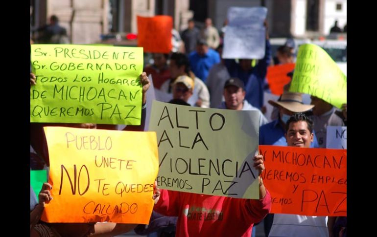 Personas sostienen cartulinas con consignas contra el Gobierno y policías federales en Morelia. REUTERS  /