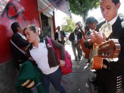 Los mariachis tocan alegremente sobre la banqueta y una estudiante debe abrirse paso para seguir su camino. A. GARCÍA  /