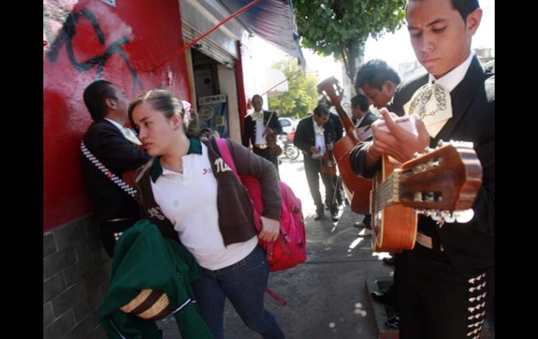 Los mariachis tocan alegremente sobre la banqueta y una estudiante debe abrirse paso para seguir su camino. A. GARCÍA  /