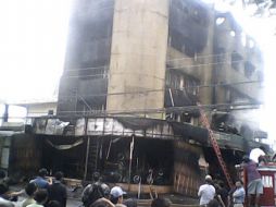 Curiosos observan el trabajo de los bomberos en la extinción del incendio. EFE  /