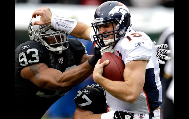 Tebow, mariscal debutante de los Broncos, es alcanzadopor dos defensivos de Oakland. AP  /