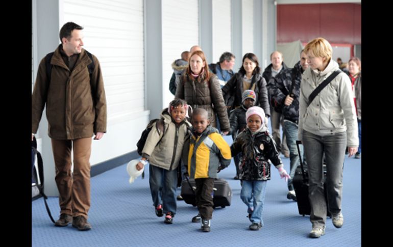 Niños haitianos con sus padres adoptivos en el aeropuerto de Roissy-en-France. AFP  /