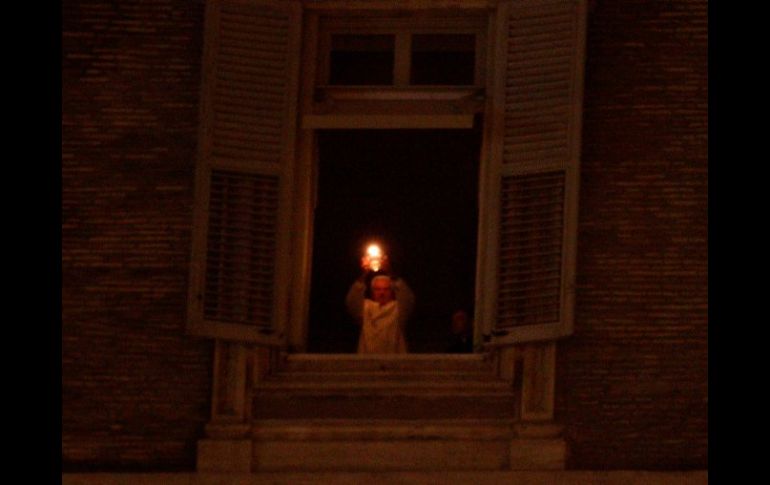 Benedicto XVI sostiene el Cirio de la Paz colocado en la ventana de su apartamento. REUTERS  /