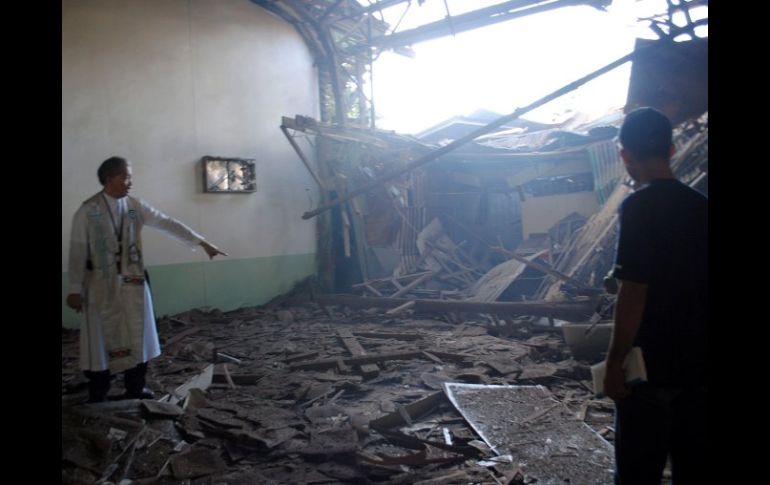 El cura Romeo Villanueva (i) inspecciona los daños tras una explosión de bomba que estalló en el tejado de la Iglesia Asturias. EFE  /