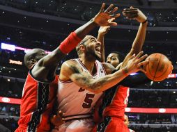 El jugador de los Toros, Carlos Boozer, logra lanzar entre Johan Petro (i) y Derrick Favors, de Nets. EFE  /