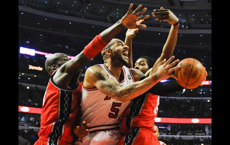 El jugador de los Toros, Carlos Boozer, logra lanzar entre Johan Petro (i) y Derrick Favors, de Nets. EFE  /