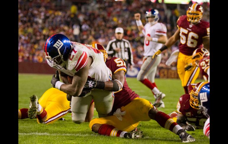 Brandon Jacobs, de Gigantes, anota, a pesar del choque con Rocky McIntosh, de Washington. AP  /