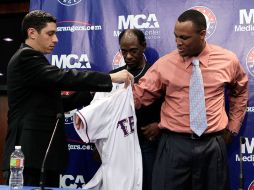 Beltré (der.) se pone la playera de Texas, ayudado por del gerente general de Texas Jon Daniels y por el mánager Ron Washington. AP  /