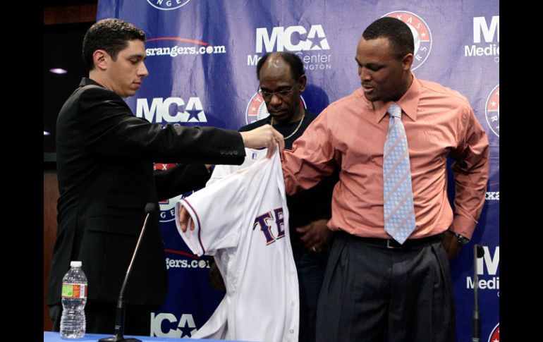 Beltré (der.) se pone la playera de Texas, ayudado por del gerente general de Texas Jon Daniels y por el mánager Ron Washington. AP  /