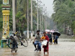 Personas caminan por  una calle inundada de la  ciudad oriental de Batticaloa  de Sri Lanka .AFP  /