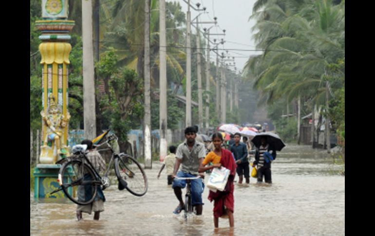 Personas caminan por  una calle inundada de la  ciudad oriental de Batticaloa  de Sri Lanka .AFP  /