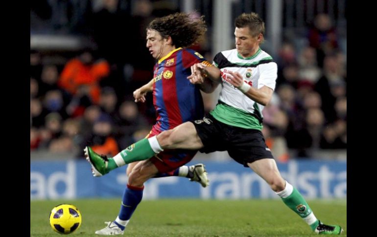 El defensa del FC Barcelona Carles Puyol (i) y el delantero del Racing de Santader Nils Markus Rosenberg luchan por el balón. EFE  /