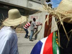 Manifestantes haitianos pintan en las paredes consignas contra los resultados de la primera vuelta electoral. AFP  /