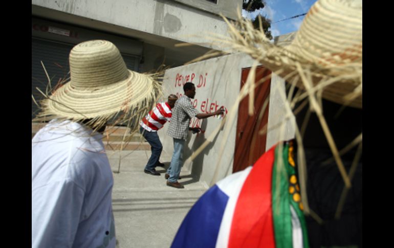 Manifestantes haitianos pintan en las paredes consignas contra los resultados de la primera vuelta electoral. AFP  /