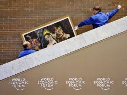 Trabajadores transportan un cuadro que adornará uno de los salones donde se realizará el Foro de Davos. AFP  /