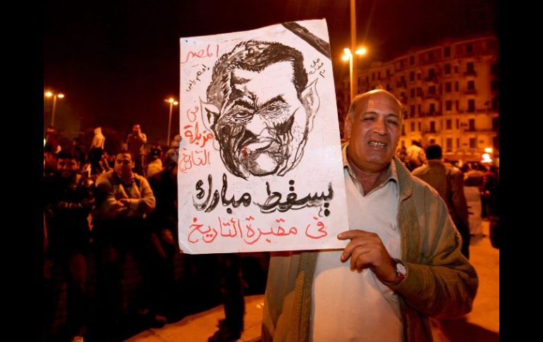 Un manifestante muestra el retrato del rostro del presidente Mubarak.  /