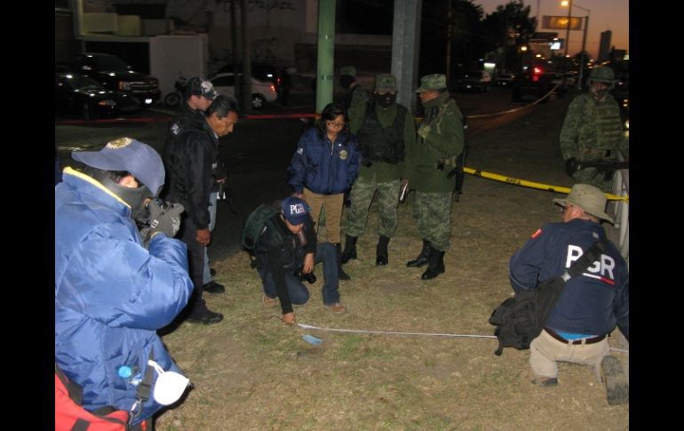 Peritos revisan el sitio donde fueron hallados los casquillos de bala calibre .9 milímetros a las afueras del bar.  M. PATIÑO  /