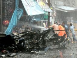 Bomberos tailandeses extinguen las llamas en un local luego de la explosión del carro bomba en el centro de Yala. EFE  /