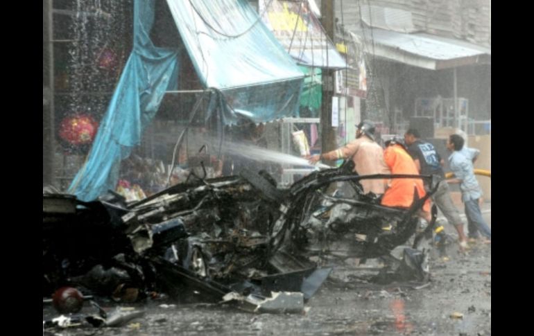 Bomberos tailandeses extinguen las llamas en un local luego de la explosión del carro bomba en el centro de Yala. EFE  /