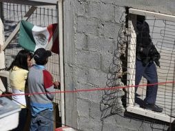 Un policía vigila las calles de Ciudad Juárez, ante la mirada de dos personas. REUTERS  /