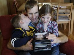 Kai Pommerenke observa fotografías familiares con su hijo Finn, a la izquierda, y su hija Ciara. AP  /