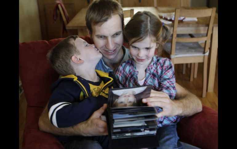 Kai Pommerenke observa fotografías familiares con su hijo Finn, a la izquierda, y su hija Ciara. AP  /