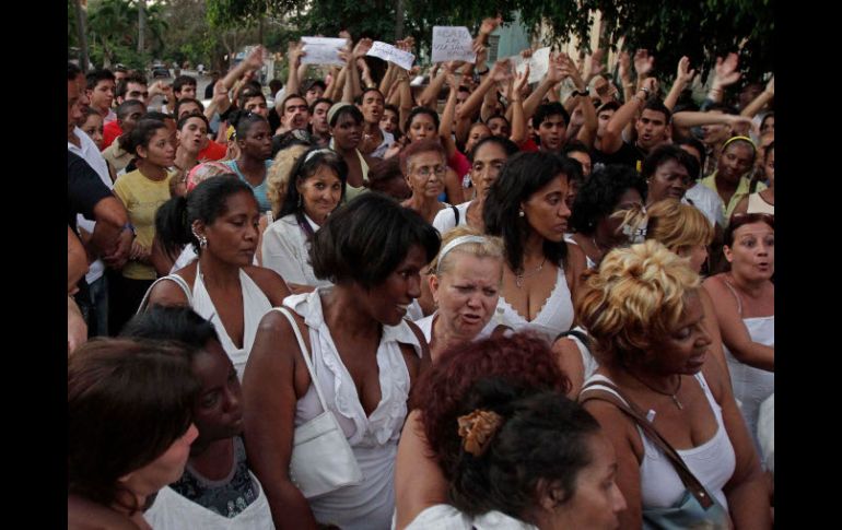 Damas de Blanco, rodeadas por oficialistas con carteles que dicen: 'abajo las viejas brutas'. AP  /