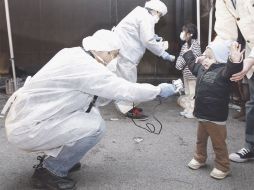 Inspectores de la Agencia para la Seguridad Nuclear de Japón checan el nivel de radiación a dos niños. REUTERS  /