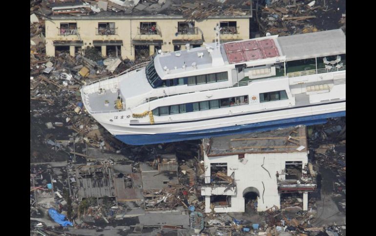 Un barco permanece hoy sobre un edificio en Otsuchi, luego del terremoto y tsunami que azotaron a Japón. AP  /