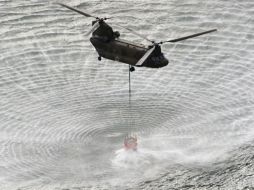 Un helicóptero carga agua para después verterla sobre el contenedor nuclear. AP  /