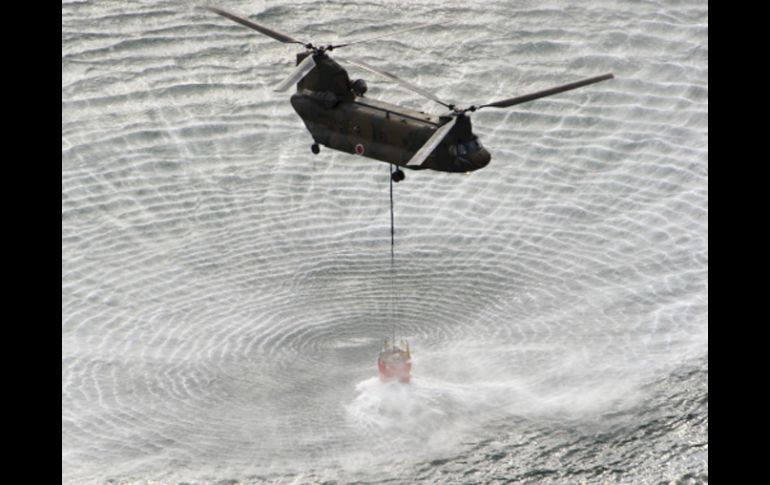 Un helicóptero carga agua para después verterla sobre el contenedor nuclear. AP  /