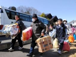 Familias cargan con sus pertenencias mientras son evacuados en masa desde Futaba. EFE  /