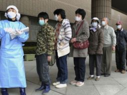 Las personas están en línea para recibir las pruebas de exposición a la radiación en  un estadio deportivo en Fukushima. AP  /