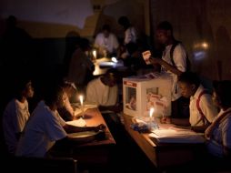 Funcionarios electorales haitianos cuentan los votos a la luz de las velas. AP  /