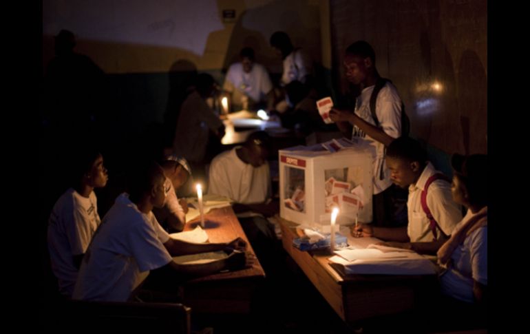 Funcionarios electorales haitianos cuentan los votos a la luz de las velas. AP  /