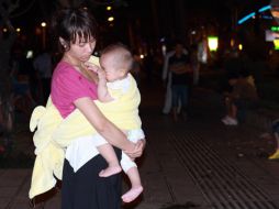 Una mujer china sostiene a su bebé afuera de su casa para evadir las réplicas. EFE  /