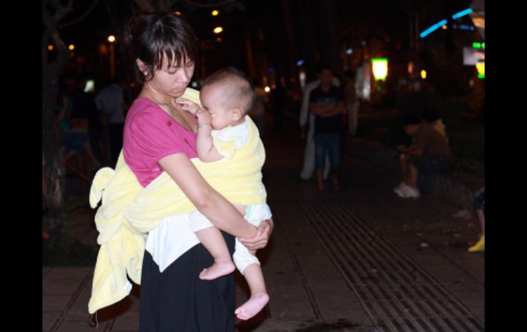 Una mujer china sostiene a su bebé afuera de su casa para evadir las réplicas. EFE  /