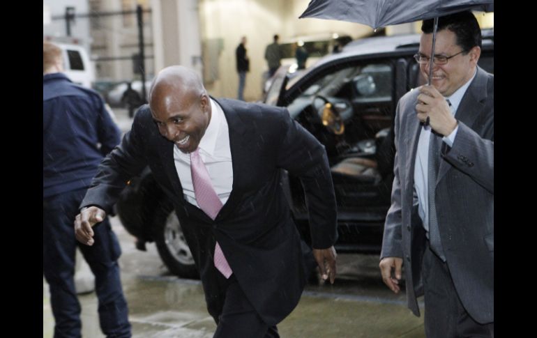 Barry Bonds intenta huir entre risas de la lluvia que cayó en San Francisco. AP  /