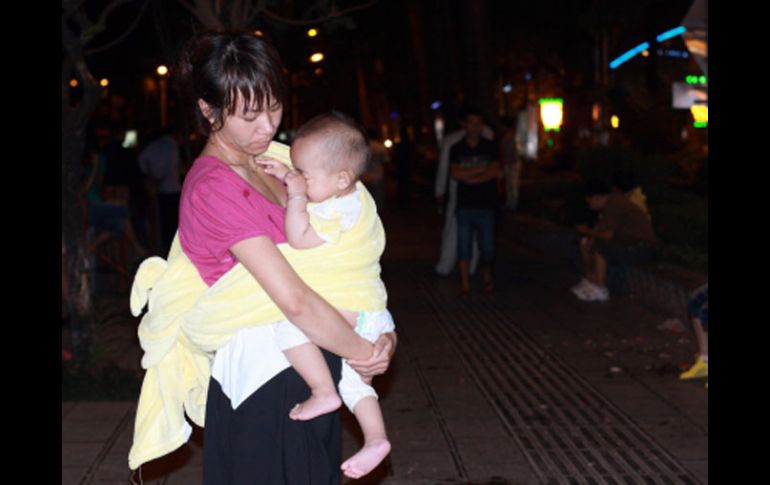 Una mujer china sostiene a su bebé afuera de su hogar, luego de las réplicas del terremoto que sacudió Birmania. EFE  /