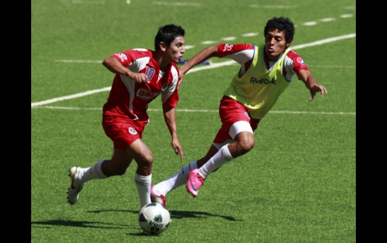 Alberto Medina (izq.) conduce el esférico en la práctica rojiblanca. MEXSPORT  /