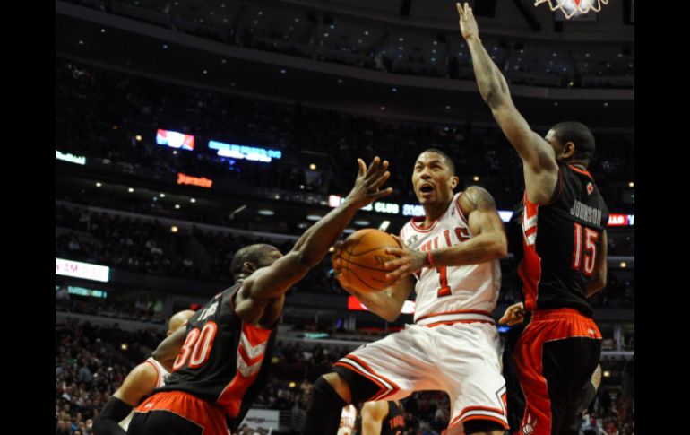 El jugador Derrick Rose (centro), de los Toros de Chicago, intenta encestar ante la marca de Reggie Evans (i) y Amir Johnson (d). EFE  /