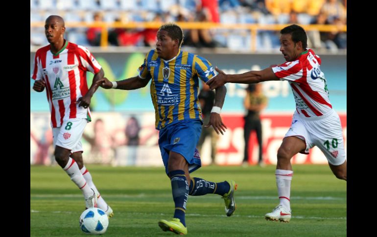 Wilmer Aguirre (c.) de San Luis escapa del necaxista Sergio Blanco, en el partido de esta tarde, en San Luis potosí. MEXSPORT  /