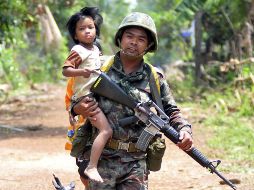 Un soldado rescata a un niño y lo aleja de un lugar donde se combaten el ejército tailandés y el camboyano. EFE  /