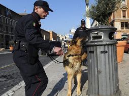 Carabineros (policía militarizada) con un perro rastreador comprueban una de las papeleras públicas cerca de la Plaza de San Pedro. EFE  /