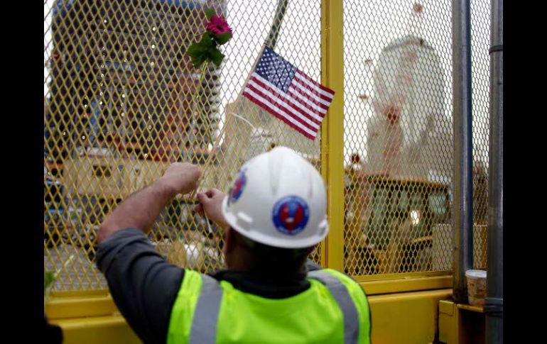 Un trabajador coloca hoy una bandera en una reja en la zona cero. AP  /