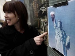 Una turista posa junto a un cartel donde se muestra a la estatua de la libertad sosteniendo la cabeza del Osama Bin Laden. AP  /